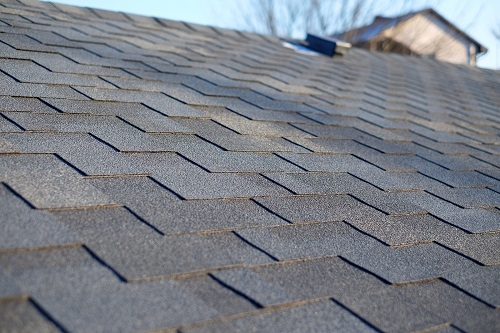 Bitumen tile roof. Kingwood roofing service for new asphalt shingles - Roofing. Close up view on Asphalt Roofing Shingles .